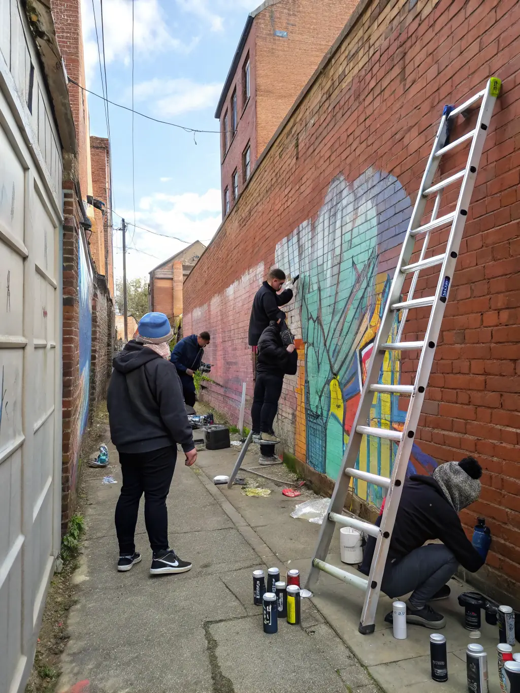 A group of young artists collaborating on a mural during an ILLIFEST workshop, showcasing the program's focus on skill development and artistic expression.